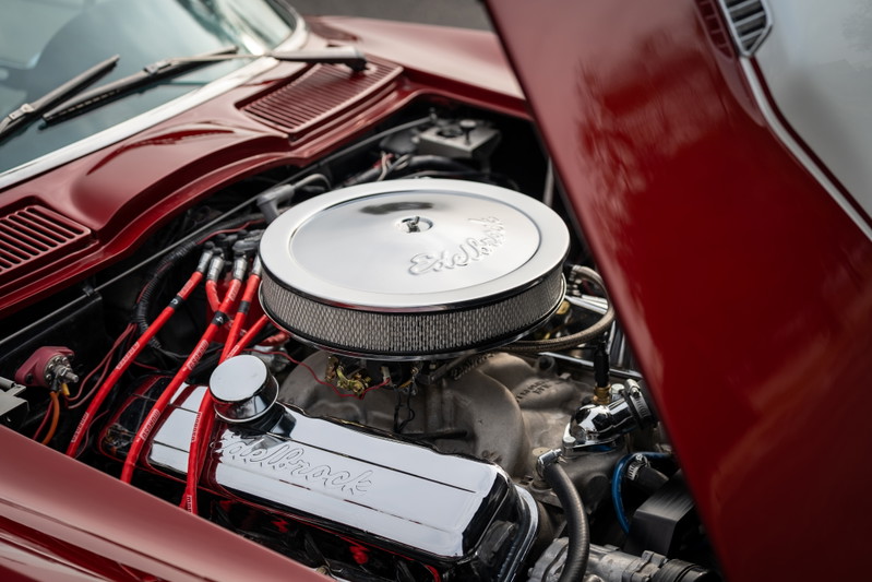 1965 Chevrolet Corvette engine bay: polished Holley valve covers, chrome air cleaner, red spark plug wires.