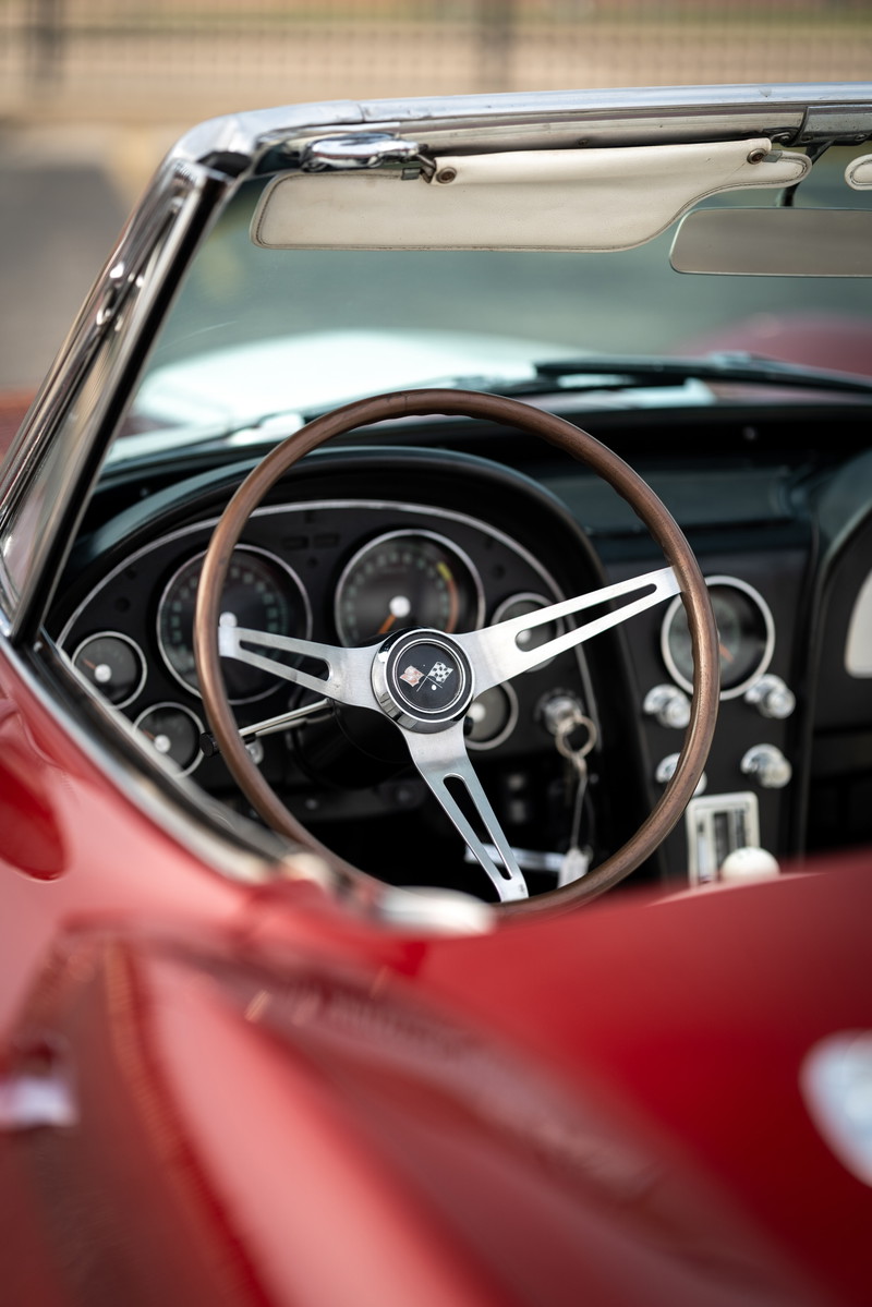 Close up of a 1965 Chevrolet Corvette Sting Ray interior, showing the wood-rimmed steering wheel & dashboard.