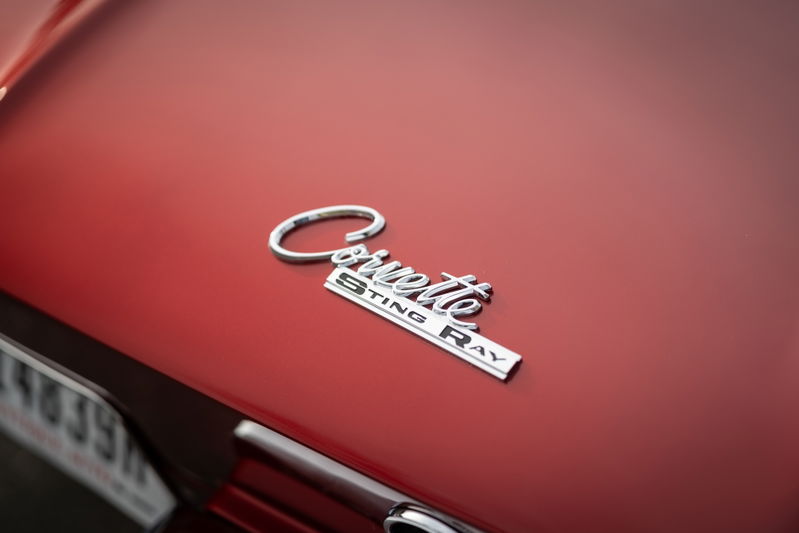 Close-up of a red 1965 Chevrolet Corvette Sting Ray emblem on the hood.