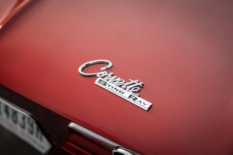 Close-up of a red 1965 Chevrolet Corvette Sting Ray emblem on the hood.