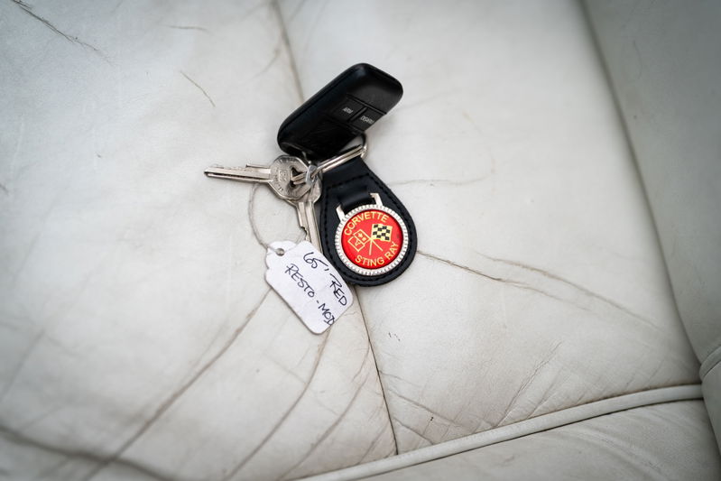 1965 Chevrolet Corvette Sting Ray keys with restoration tag and checkered flag emblem on white leather.