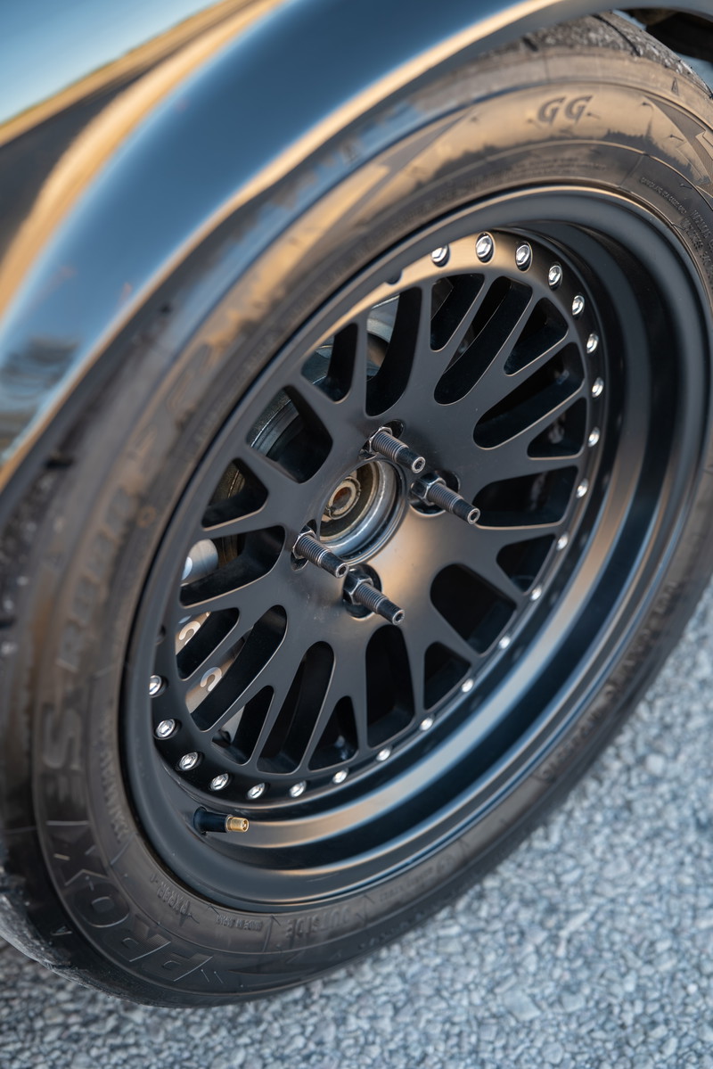 Black 1989 BMW 325is with black mesh alloy rims and performance tires.