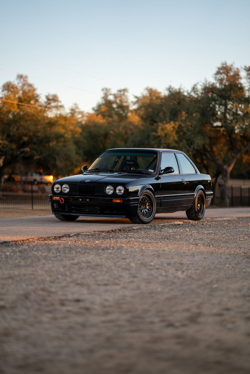 Black 1989 BMW 325is LS1 with mesh rims and red tow hook.