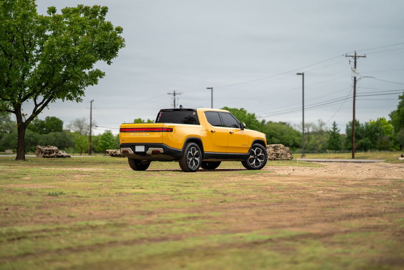 Yellow Rivian R1T electric truck with distinct rims and black trim.
