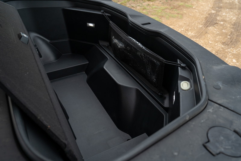 Rivian R1T electric pickup truck frunk interior with storage net and lighting.