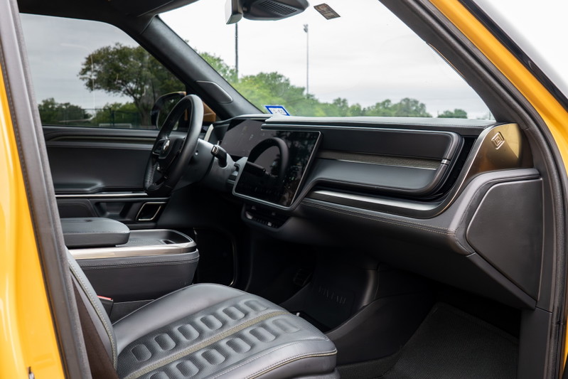 Interior of a yellow 2022 Rivian R1T showing the dashboard, steering wheel, and driver's seat.