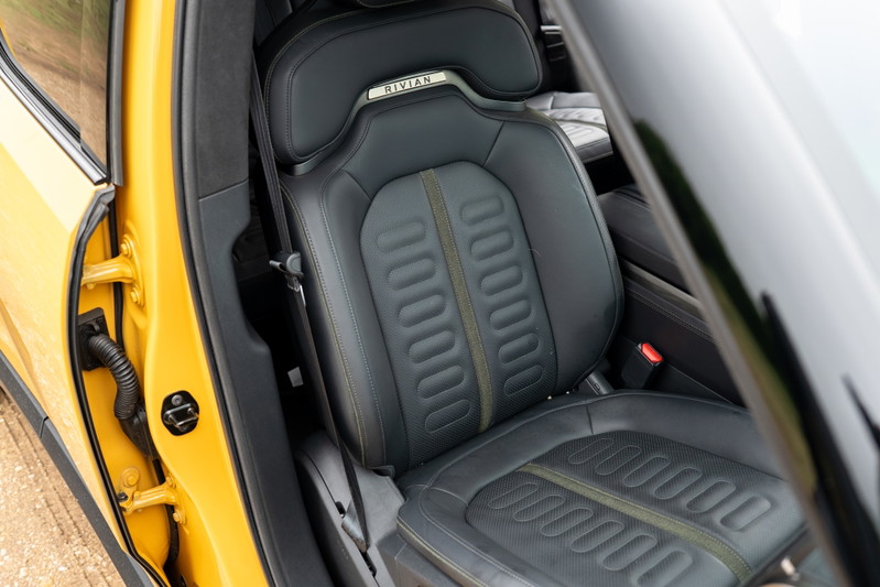 Yellow 2022 Rivian R1T driver's seat with perforated leather and olive green trim.