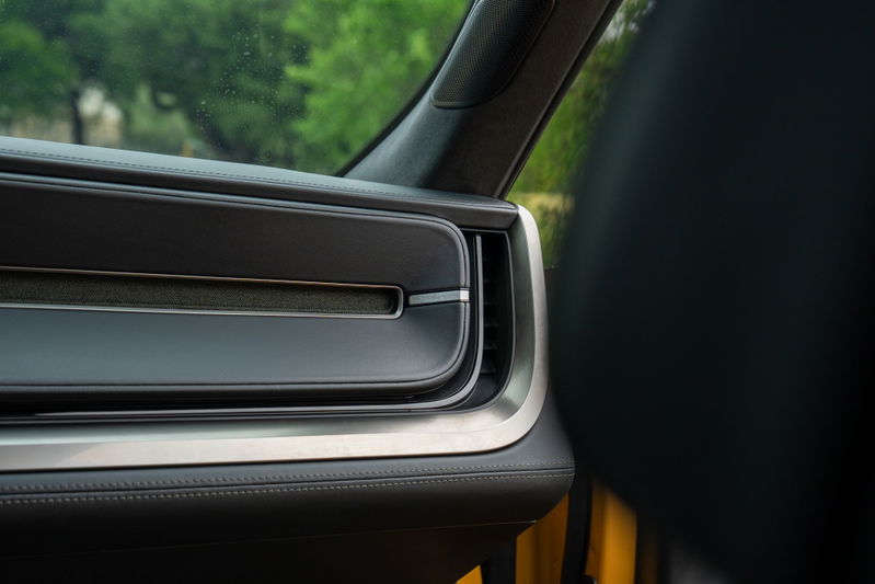 Close-up of a yellow Rivian R1T's interior, showing a sleek dashboard air vent with silver trim.
