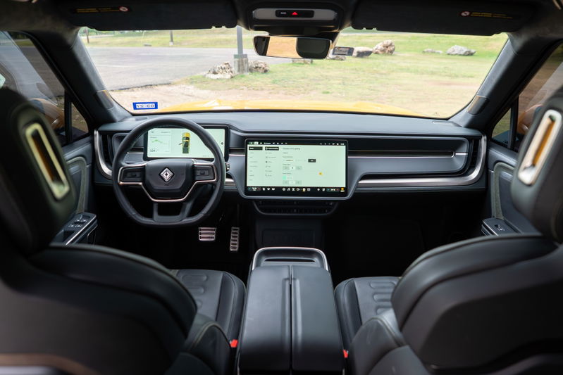 2022 Rivian R1T interior: Minimalist dash with large touchscreens, digital cluster, and luxurious black leather trim.