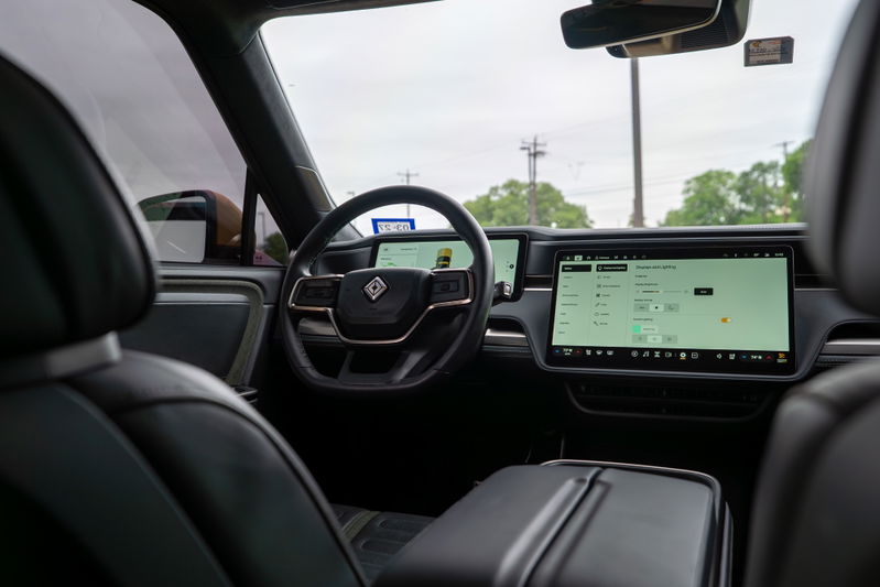 Interior of a yellow 2022 Rivian R1T showing the dashboard, steering wheel, and large infotainment screen.