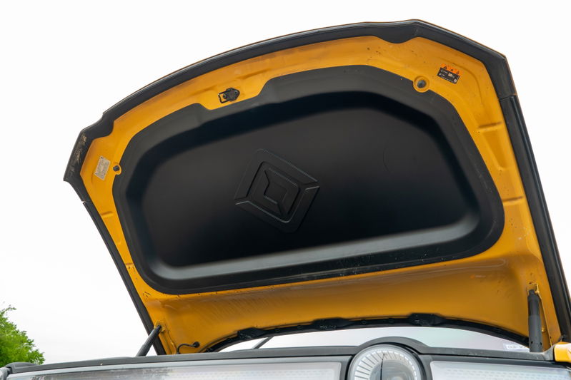 Open hood of a yellow Rivian R1T, showing insulation and latch mechanism.