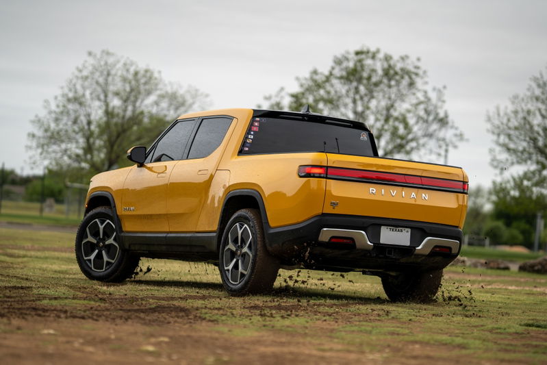Yellow 2022 Rivian R1T with black accents and multi-spoke rims driving off-road.