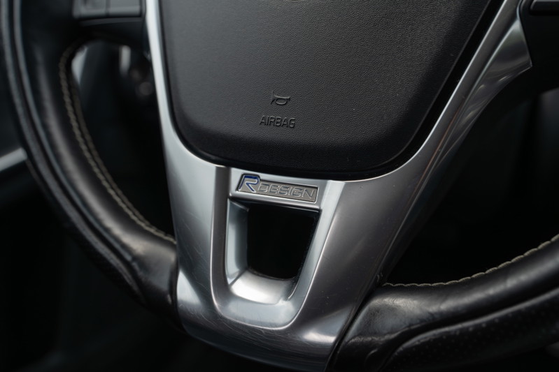 Close-up of a 2015 Volvo V60 R-Design steering wheel with brushed metal trim and R-Design badging.