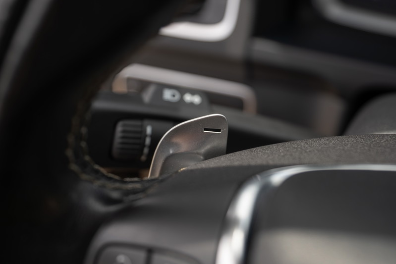 Close-up of a silver paddle shifter on a black leather steering wheel of a 2015 Volvo V60 R-Design Polestar.