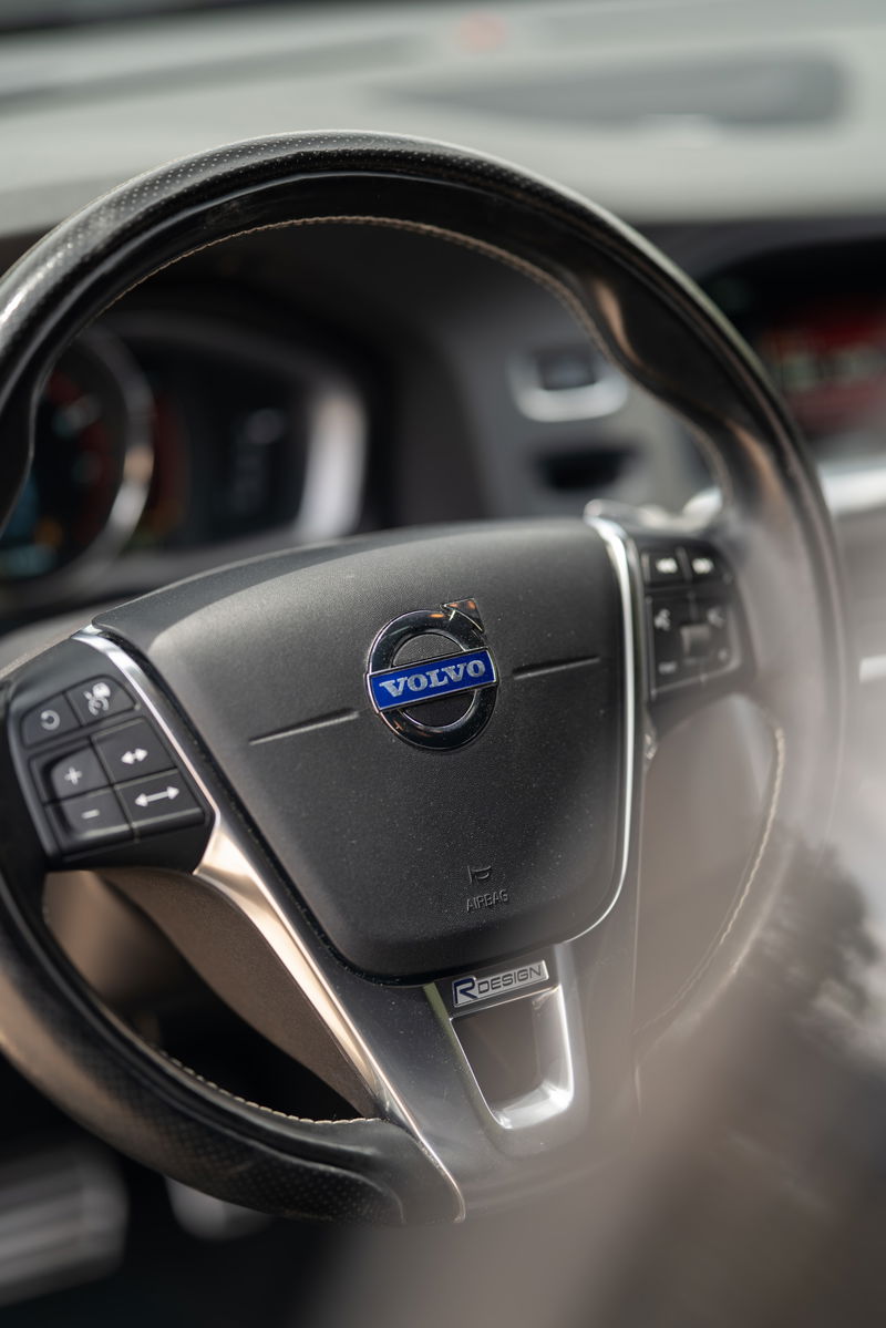 Close-up of a black Volvo V60 R-Design steering wheel with R-Design badge and Volvo logo.