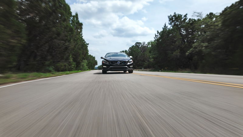 Black 2015 Volvo V60 R-Design Polestar speeding on a rural road.