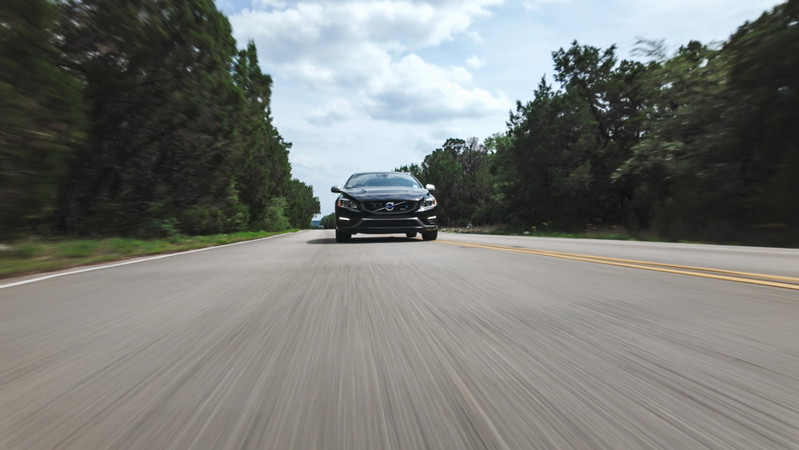 Black 2015 Volvo V60 R-Design Polestar speeding on a rural road.