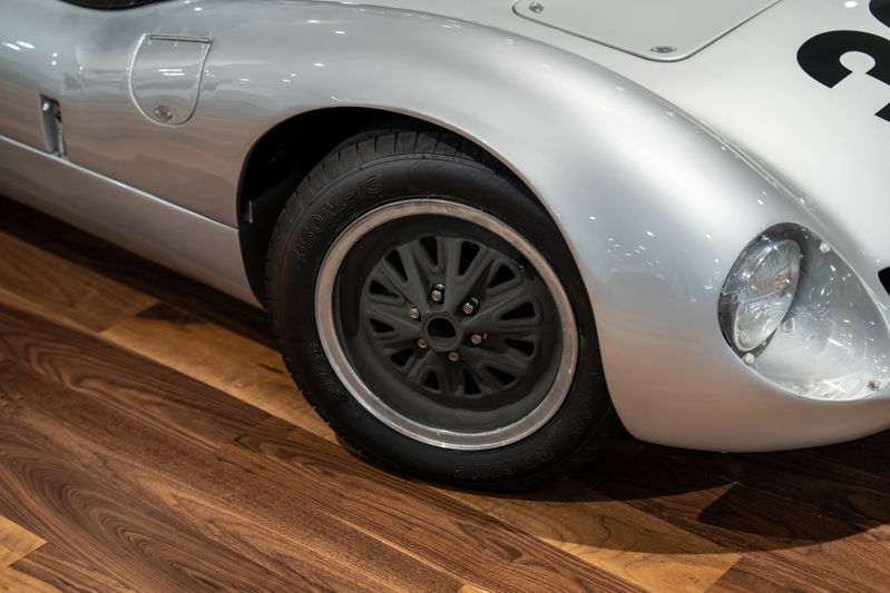 Close-up of a silver 1964 Elva Porsche 4-Cam with a black multi-spoke rim and polished lip.