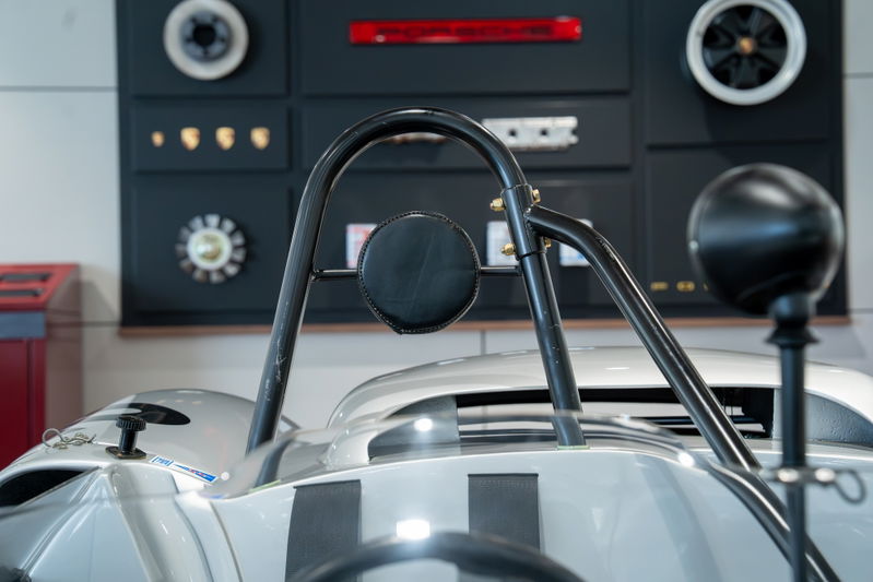 Close-up of a vintage silver Elva Porsche 4-cam race car with a roll bar and black trim.