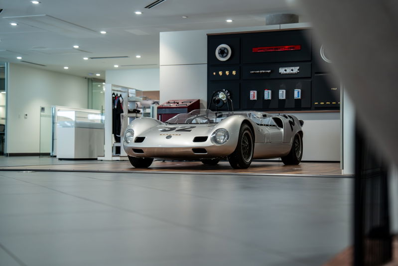 A silver 1964 Elva Porsche 4-Cam race car with black rims and racing livery.