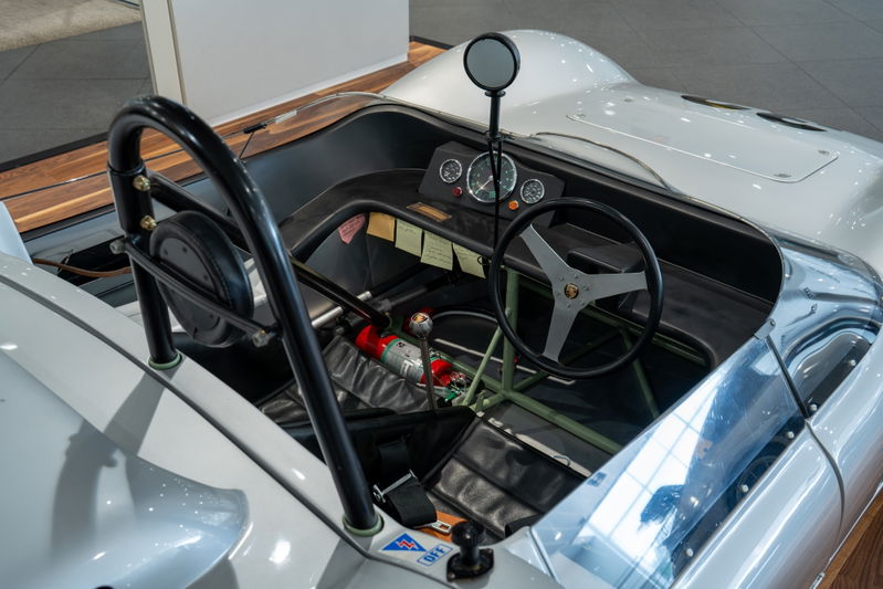 Close-up interior of a 1964 Elva Porsche 4-cam race car, showing the steering wheel, dash, and roll bar.