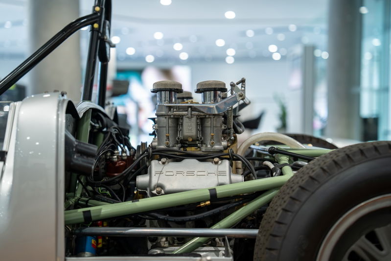 Close-up of a 1964 Elva Porsche 4-cam engine. Silver body panels, dual carburetors.
