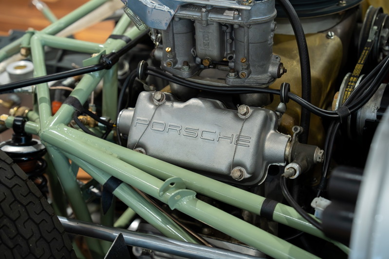 Close-up of the Porsche 4-cam engine in a vintage Elva race car with green chassis tubing.