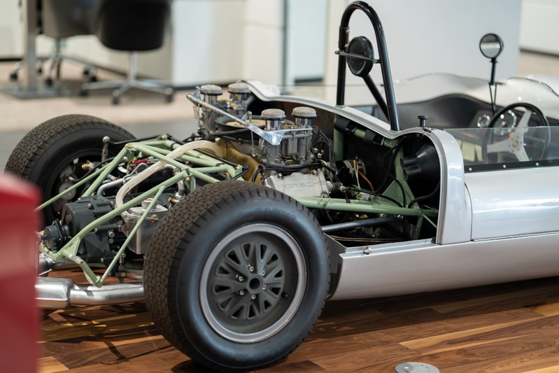 1964 Elva Porsche 4-Cam race car with exposed engine, gray alloy rims, and roll hoop.