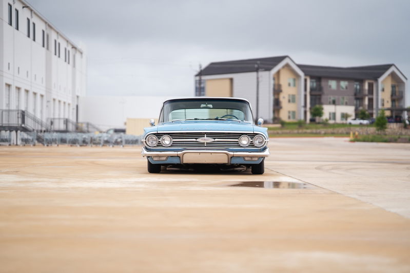 Front view of a light blue 1963 Chevrolet Impala lowrider with chrome trim and classic rims.