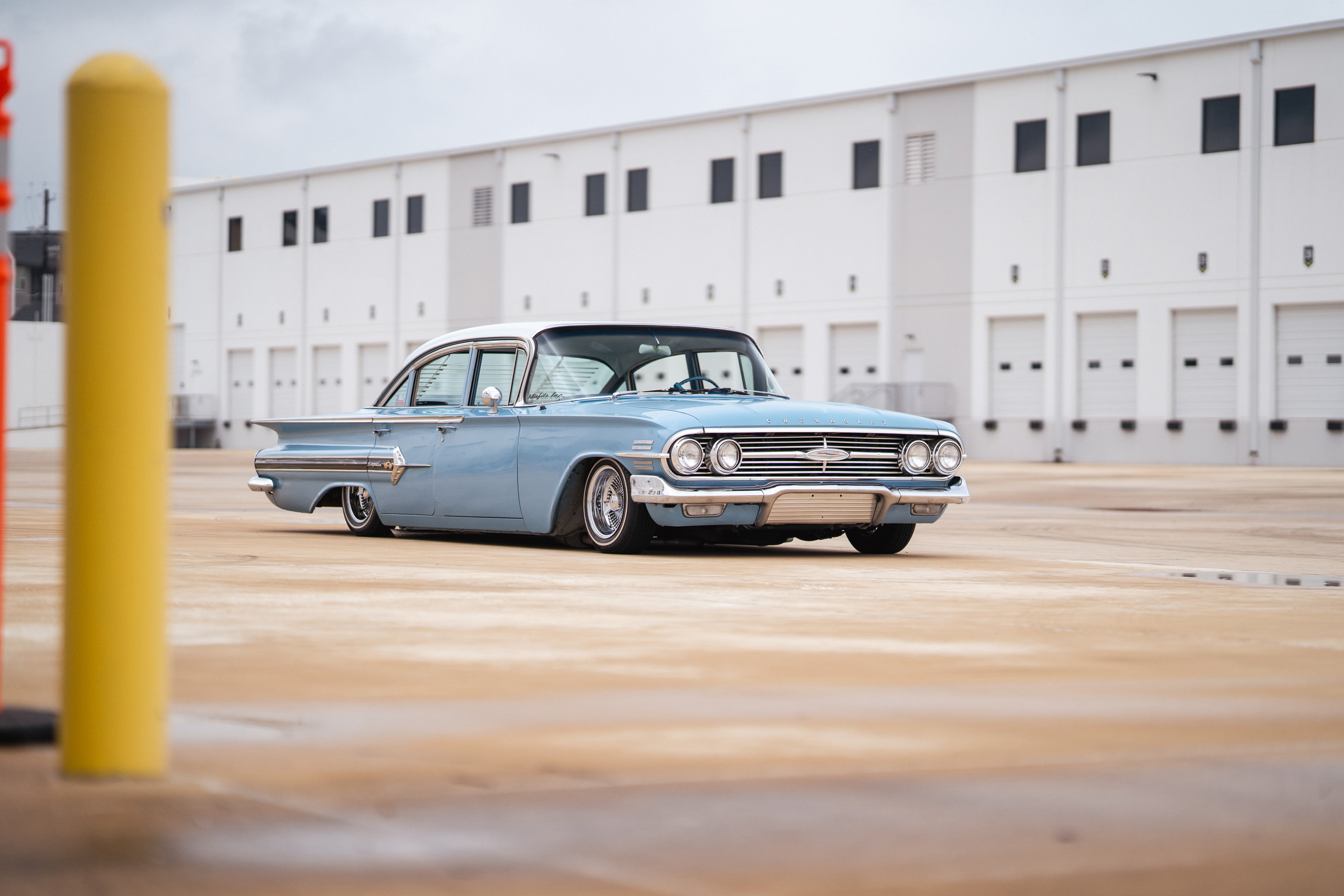 1960 blue Chevrolet Impala lowrider with chrome rims and white roof trim.