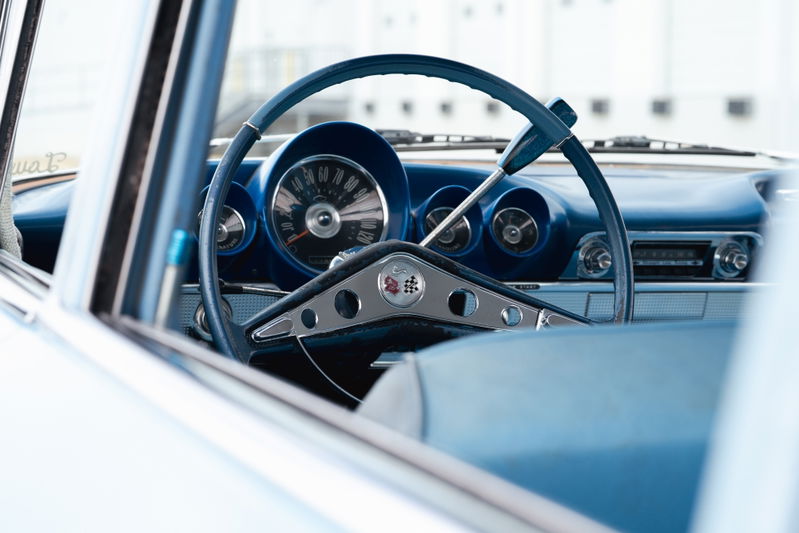 Close-up of a 1963 blue Chevrolet Impala lowrider interior, featuring a turquoise steering wheel and dashboard trim.
