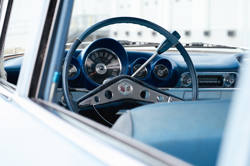 Close-up of a 1963 blue Chevrolet Impala lowrider interior, featuring a turquoise steering wheel and dashboard trim.