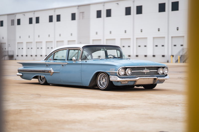 1960 blue Chevrolet Impala lowrider with chrome rims and whitewall tires.