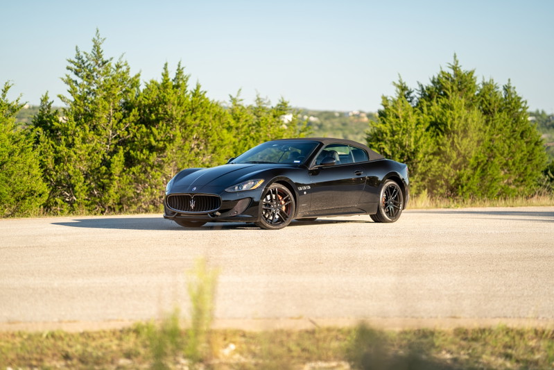 Black 2016 Maserati GranTurismo convertible with black rims on a road.