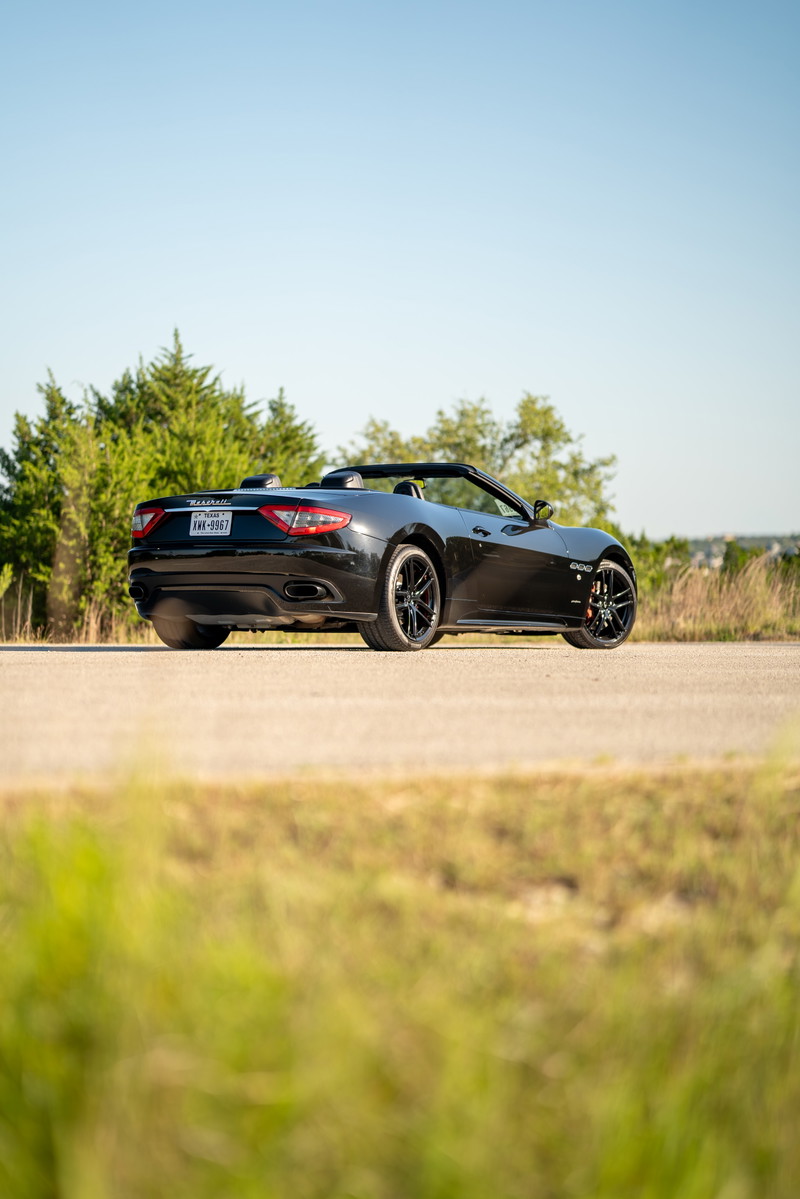 Black 2016 Maserati GranTurismo convertible with black rims and red brake calipers.