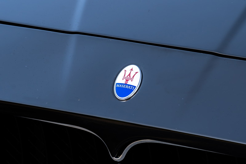 Close-up of a Maserati GranTurismo's badge on its black hood.