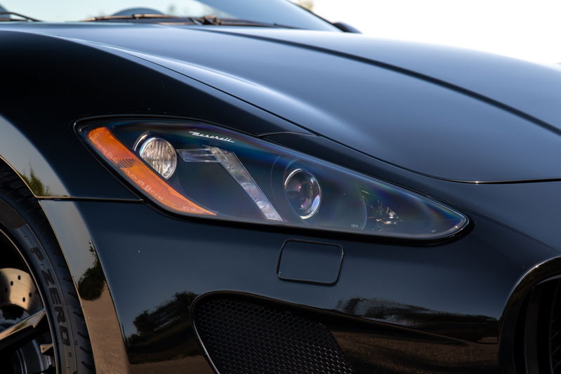 Close-up of a black 2016 Maserati GranTurismo headlight and front fender.