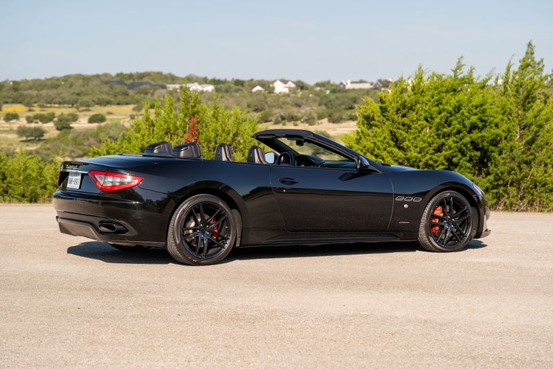 Black 2016 Maserati GranTurismo convertible with black rims and red brake calipers.