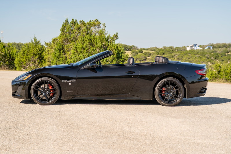 Black 2016 Maserati GranTurismo convertible with black rims and red brake calipers.