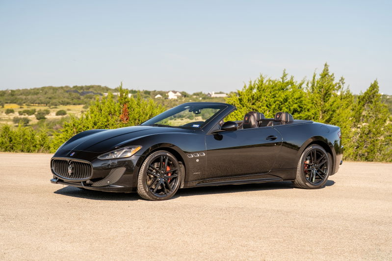Black 2016 Maserati GranTurismo Convertible with black rims and red brake calipers.