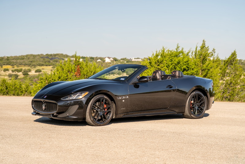 Black 2016 Maserati GranTurismo Convertible with black rims and red brake calipers.
