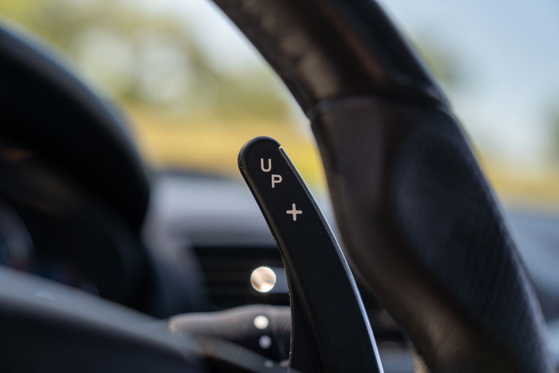 Maserati Granturismo steering wheel paddle shifter with "UP" and "+" markings.