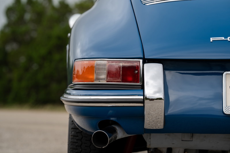 Close-up of a blue 1965 Porsche 912's rear bumper, taillight, and exhaust.