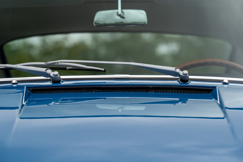 Close-up of vintage blue Porsche 912 hood, windshield wipers and interior mirror.