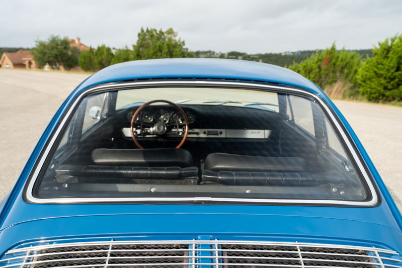 Blue 1965 Porsche 912 interior, rear view. Vintage wooden steering wheel, black seats.