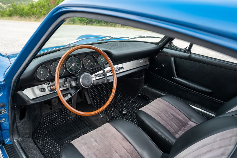 Interior of a 1965 blue Porsche 912, featuring a wood-rimmed steering wheel and classic gauges.