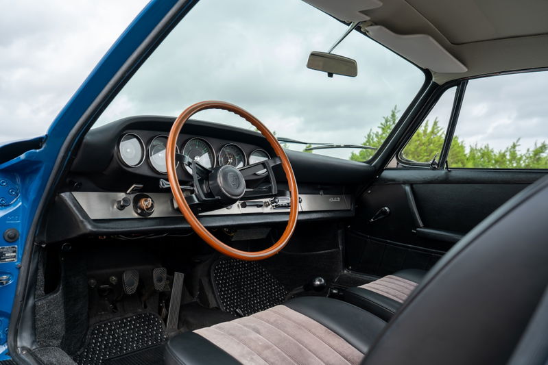 1965 Porsche 912 interior in blue, featuring a wooden steering wheel and tan striped seats.