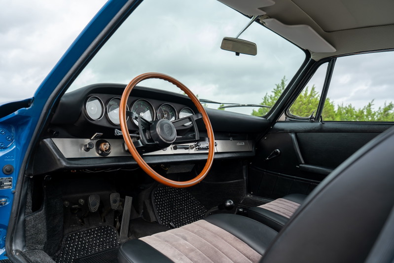 1965 Porsche 912 interior in blue, featuring a wooden steering wheel and tan striped seats.