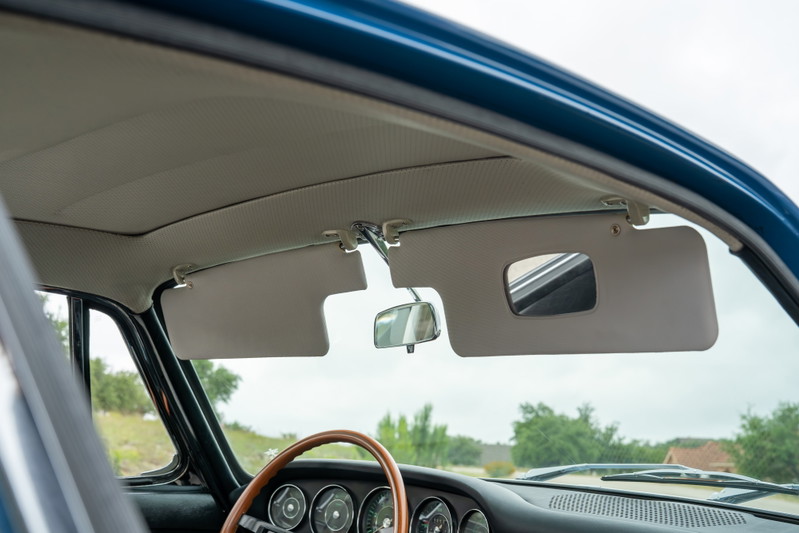 Interior of a blue 1965 Porsche 912, showing sun visors with vanity mirror and rearview mirror.