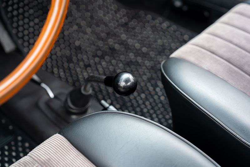 Interior of a 1965 blue Porsche 912, showing the wooden steering wheel, shifter, and corduroy seats.